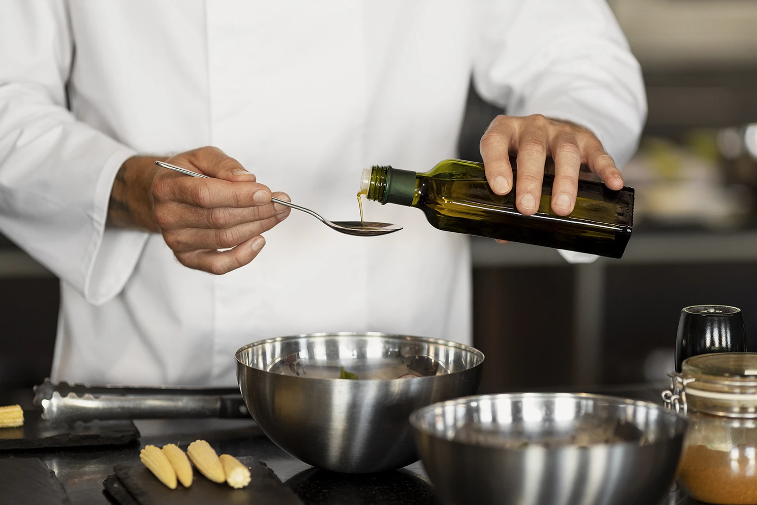Koch gießt natives Olivenöl extra auf einen Löffel, um es vor dem Kochen zu verkosten und seine Qualität zu prüfen